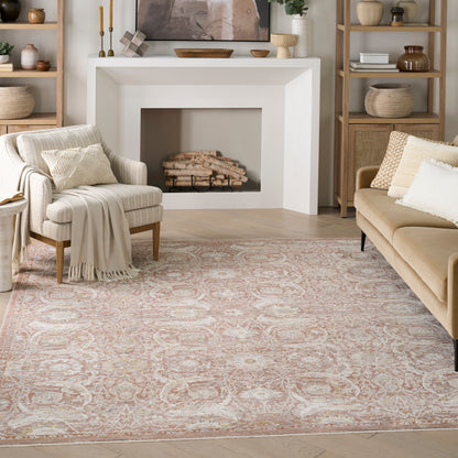 Neutral living room with a patterned pink-beige area rug, cream armchair, tan sofa, white fireplace, and wooden shelves.