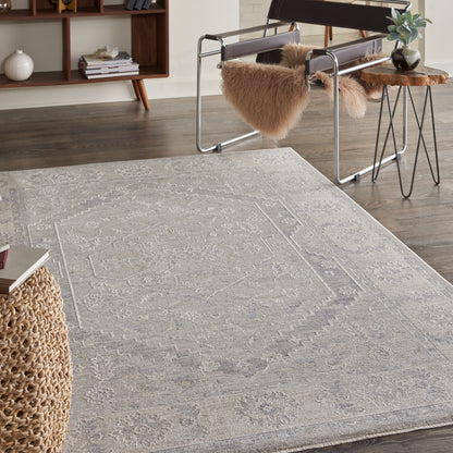 Light gray oriental rug with a subtle geometric pattern on dark wood floor.