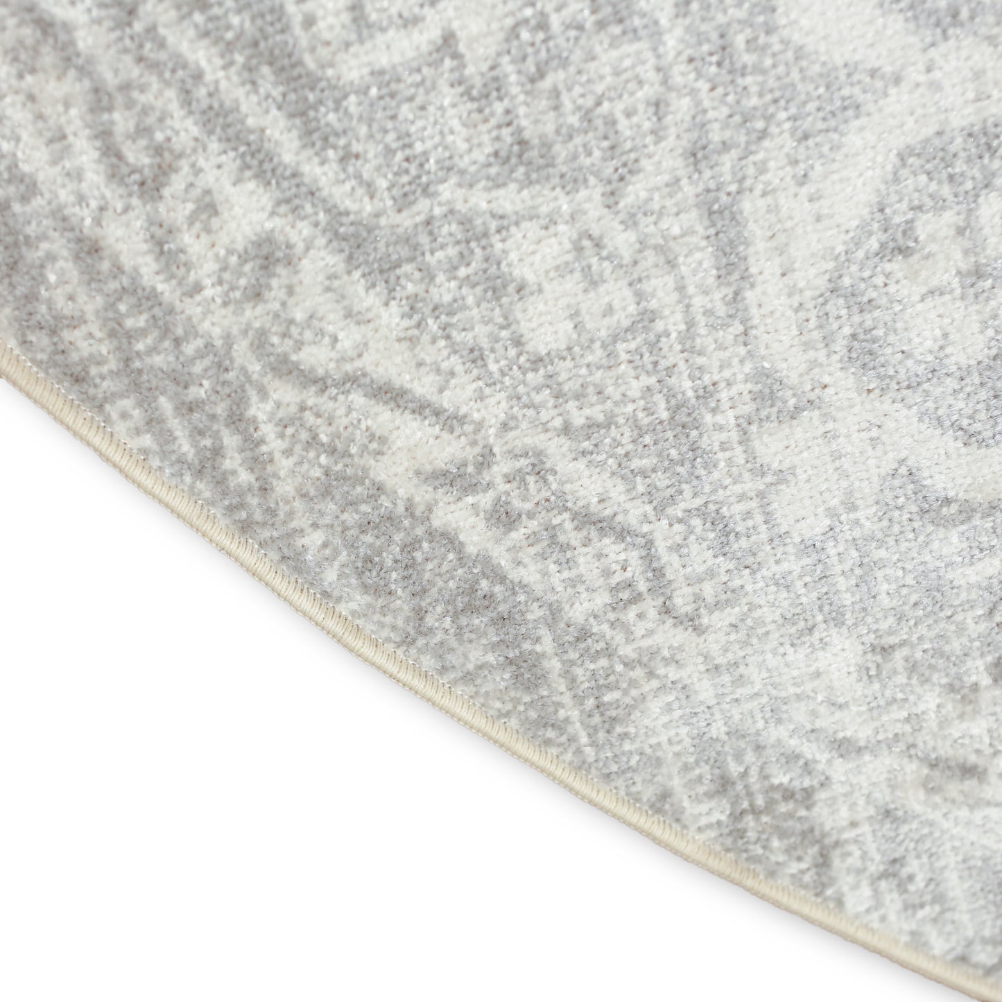 Close-up of a gray and ivory patterned rug with light beige binding along the curved edge.