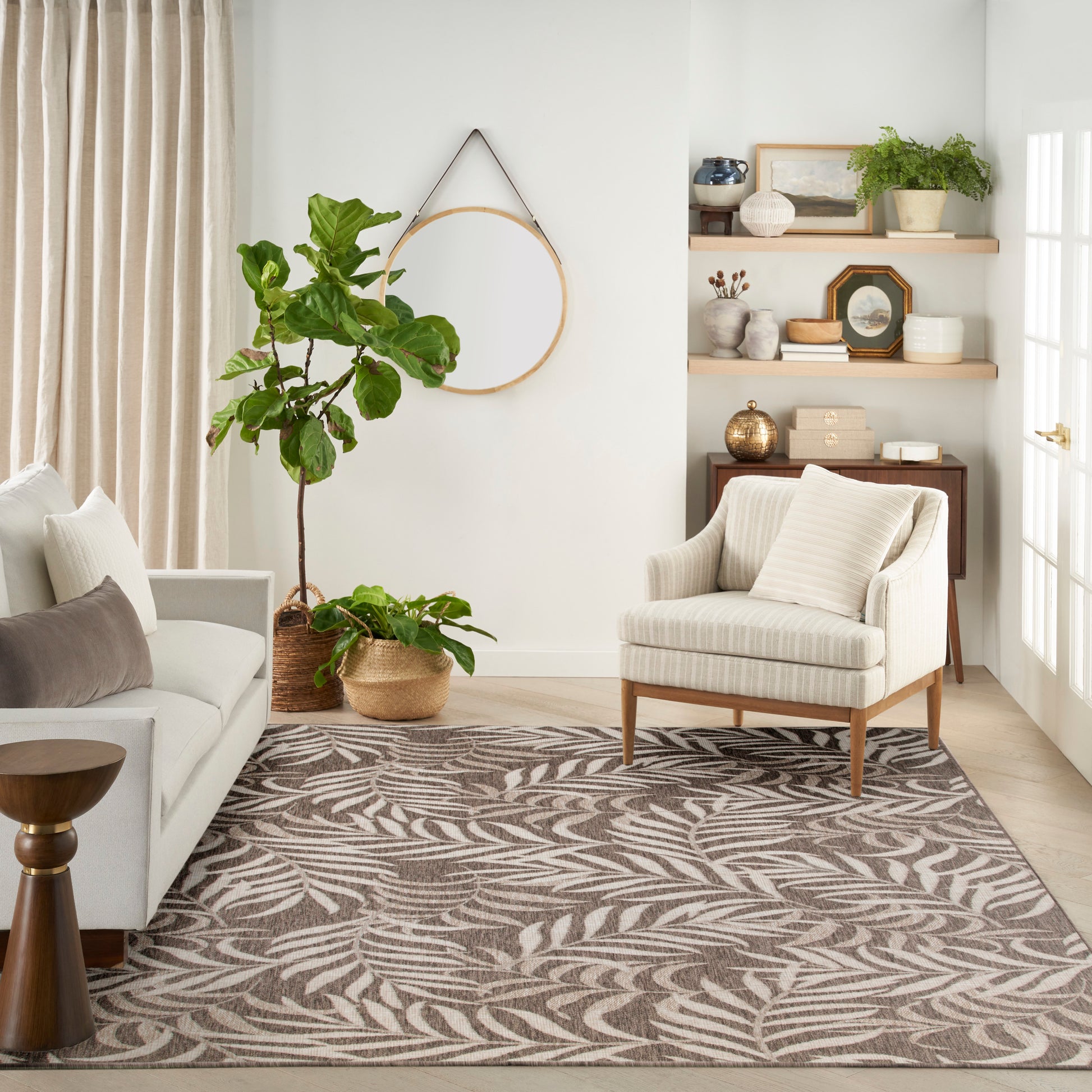 Neutral living room with beige striped armchair, light gray sofa, fig plant, baskets, and a taupe leaf-pattern rug.
