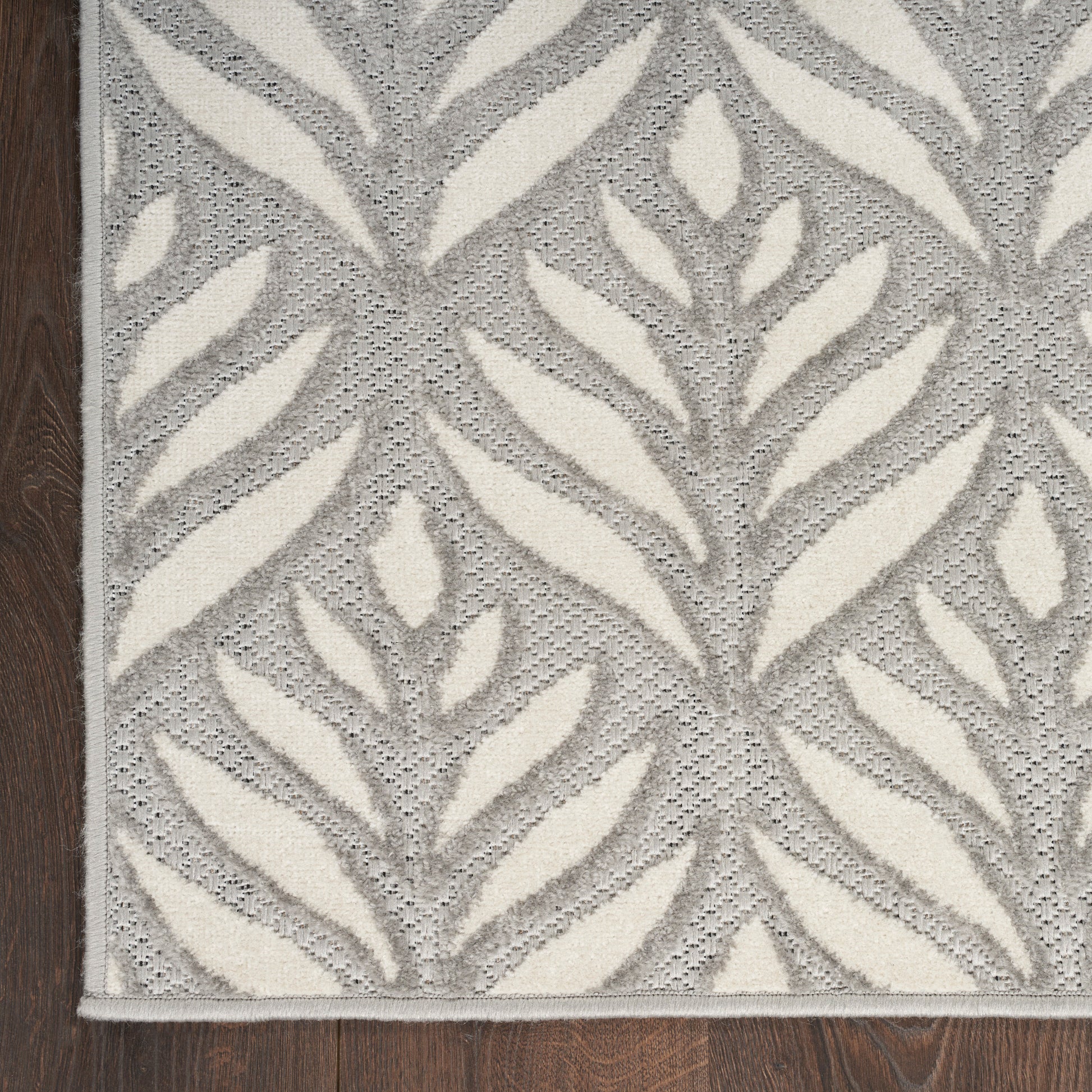 Grey rug with cream leaf pattern, woven texture, rectangular shape; ideal for living room or hallway.