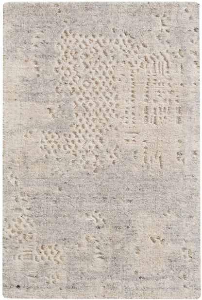 Beige textured area rug with abstract patchwork patterns in cream and taupe tones.