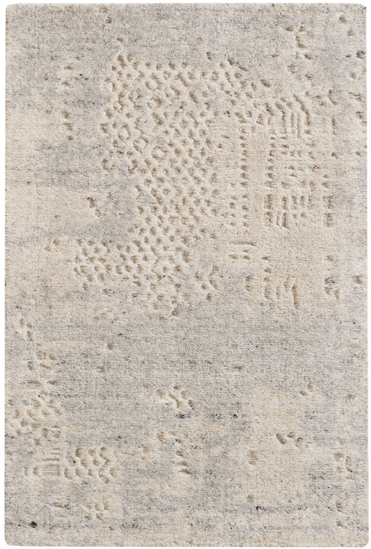 Beige textured area rug with abstract patchwork patterns in cream and taupe tones.