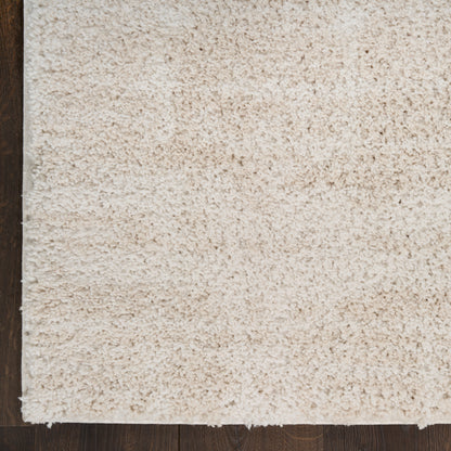 Cream shag rug with plush fibers on dark wood floor, corner edge visible.