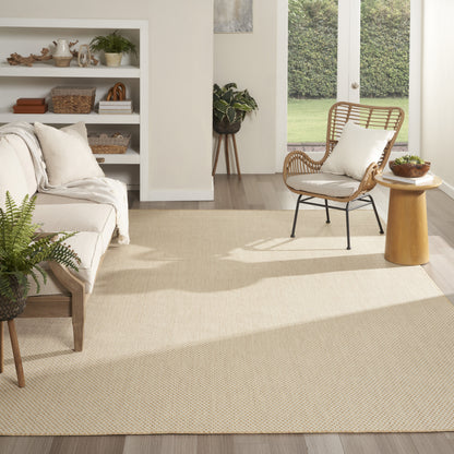 Bright living room with beige woven rug (9' x 12'), light sofa, rattan chair, white cushion, wooden side table, and doors to the garden.