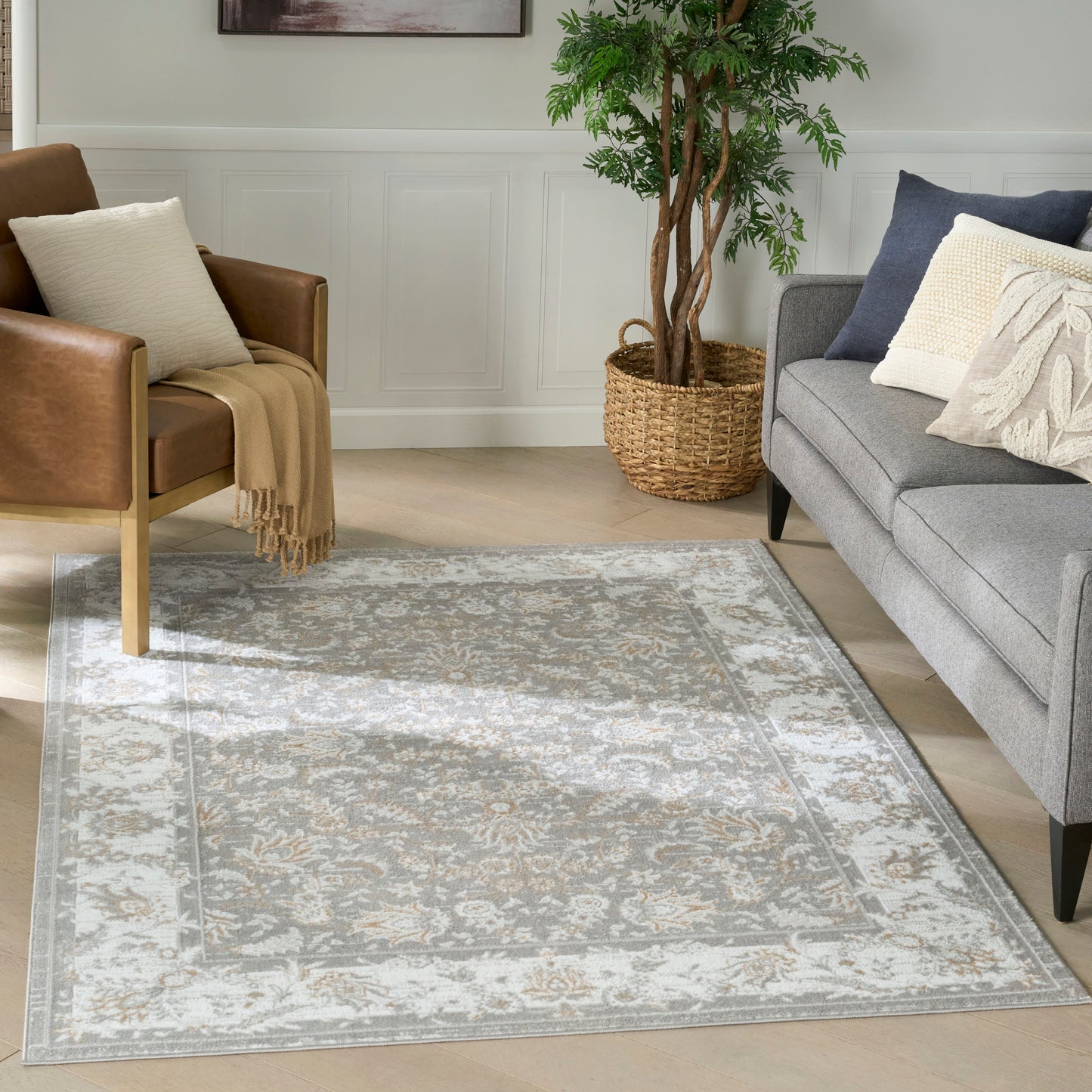 Light gray and beige patterned area rug in a modern living room with a gray sofa, brown leather chair, and a potted plant.