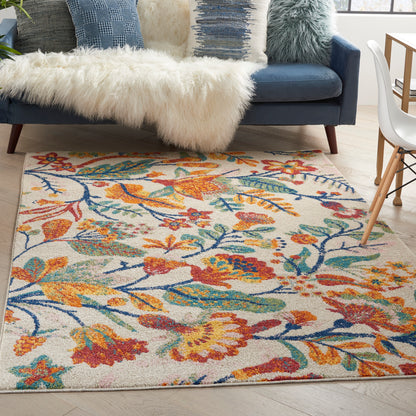 Cream area rug with vibrant orange, teal, and blue floral pattern under a blue sofa with a white faux-fur throw.