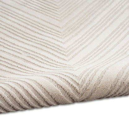 Beige plush throw blanket with raised chevron stripes and soft textured surface, folded at corner.