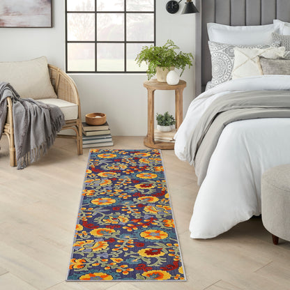 Elongated floral woven runner rug in navy with orange and yellow flowers and grey-green leaves on light wood bedroom floor.