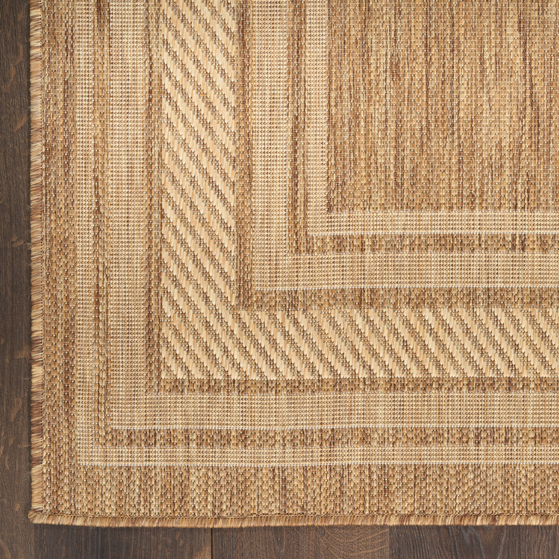 Natural beige jute rug with braided concentric rectangles and framed borders on dark wood floor.