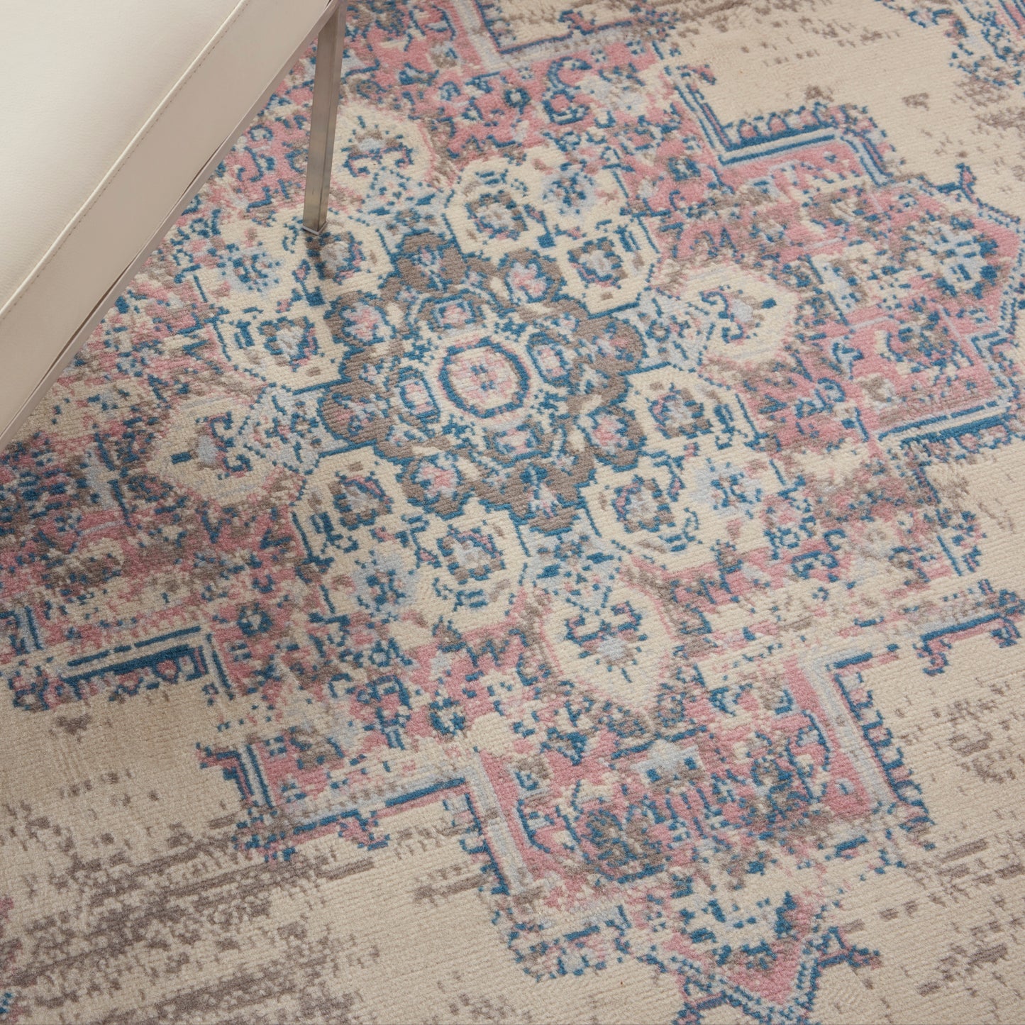 Pastel oriental rug with blue, pink & beige medallion pattern; distressed vintage look under a cream sofa leg.