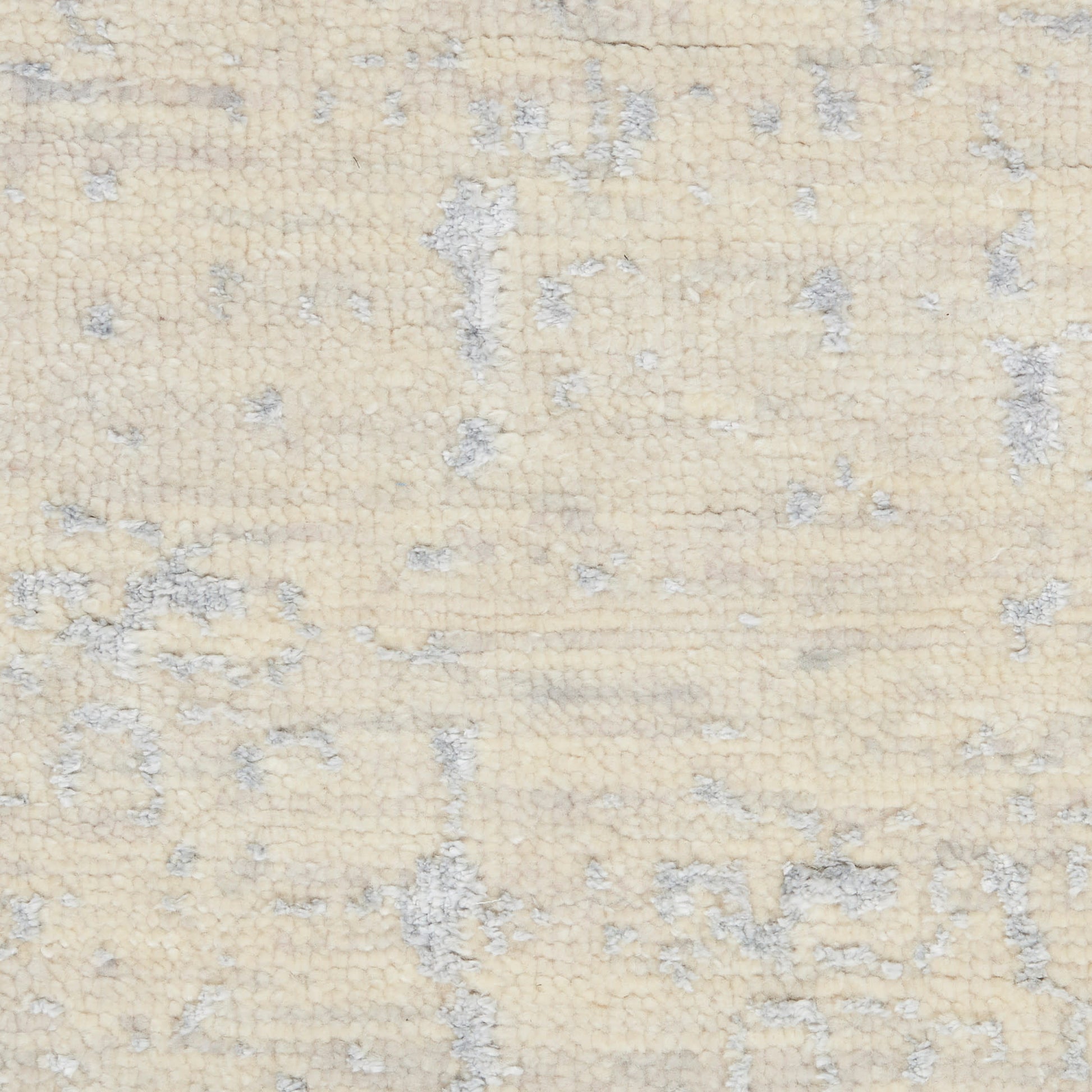 Cream-beige rug close-up with a soft, plush pile and a light gray distressed abstract pattern.
