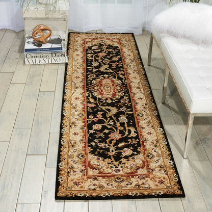 Long oriental rug runner with black center and ornate gold-red floral border, beige accents, laid on light wood floor.