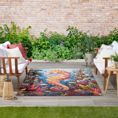 Outdoor patio lounge with white cushioned wooden chairs, vibrant seahorse rug, lush greenery backdrop and lanterns.