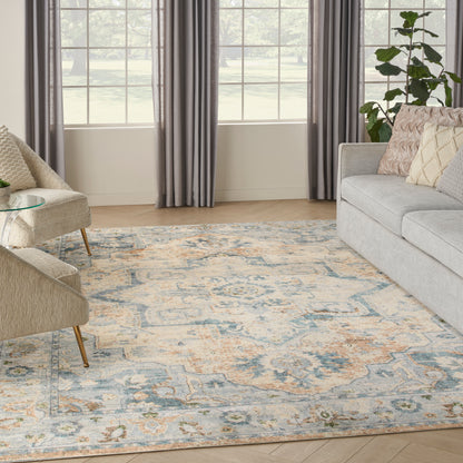 Living room with a large pastel patterned area rug in blue, cream and peach, beige chairs, gray sofa, and gray curtains.