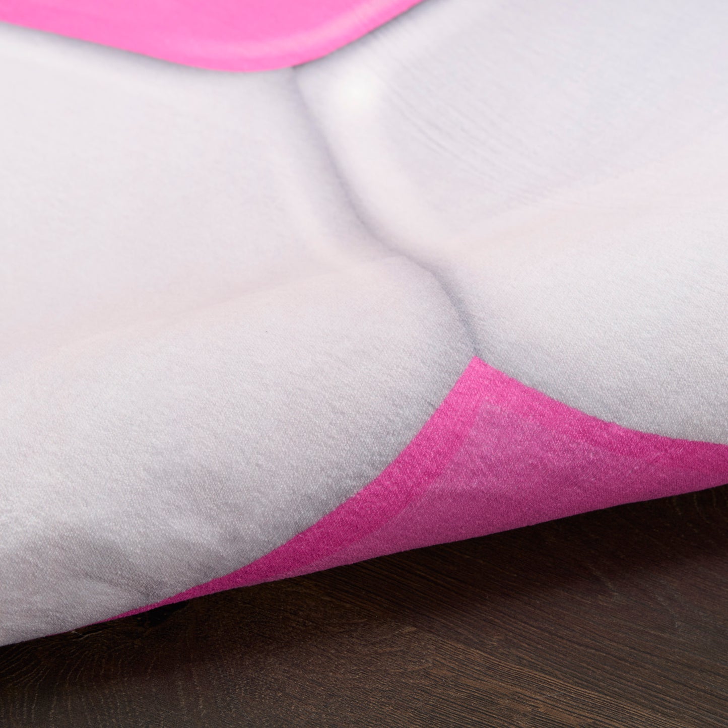 Close-up of soft gray cushion fabric with bright pink geometric triangles and curved seam details.
