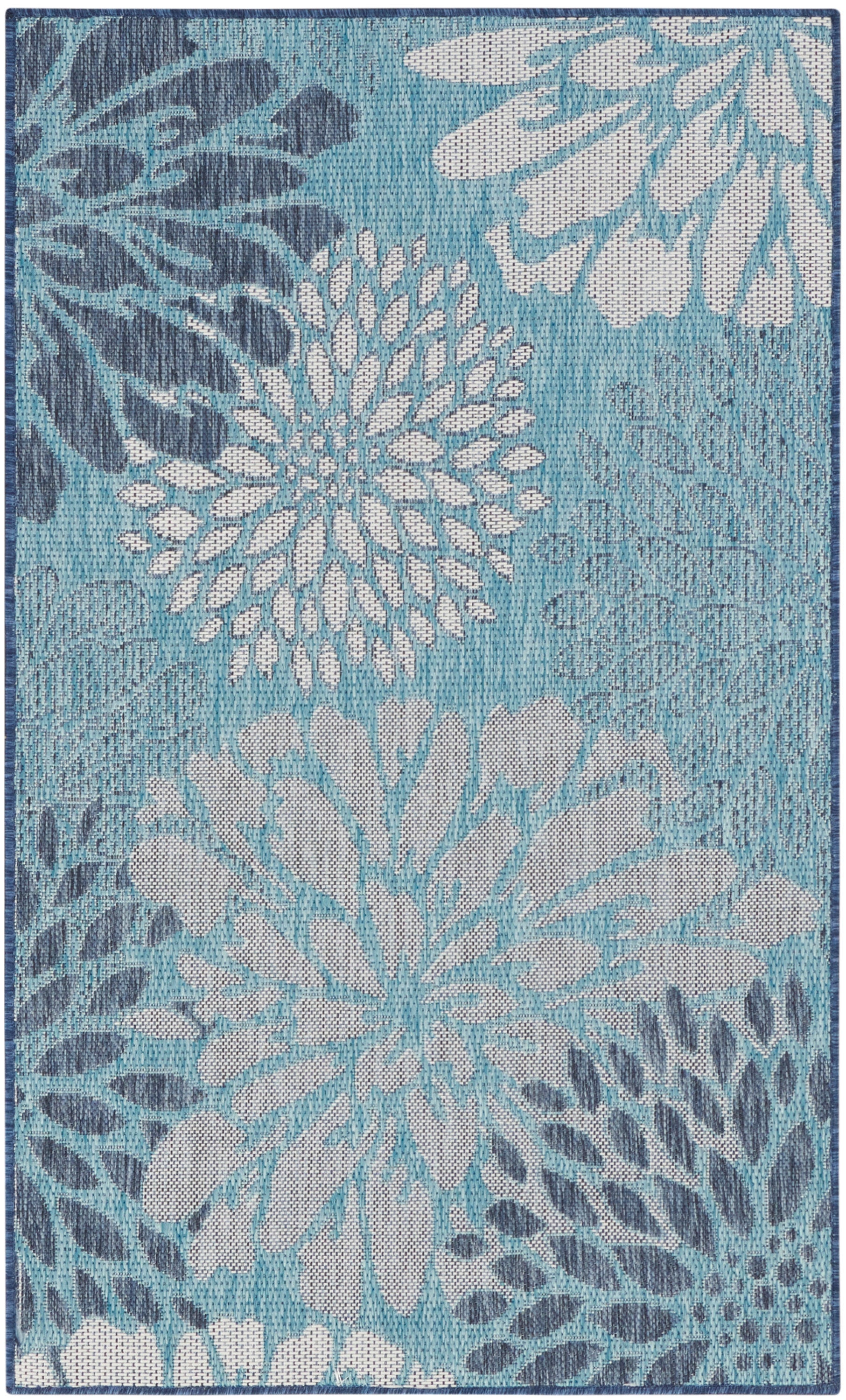 Teal-blue area rug with oversized white and light-blue floral motifs in a textured weave.