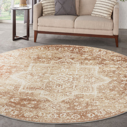Round beige oriental-style rug with ivory geometric motif on a gray floor beside a cream sofa.
