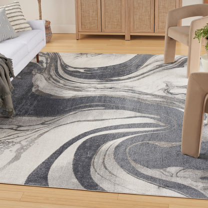 Abstract swirl gray and cream area rug on wooden floor, with beige sofa and woven-front cabinet.