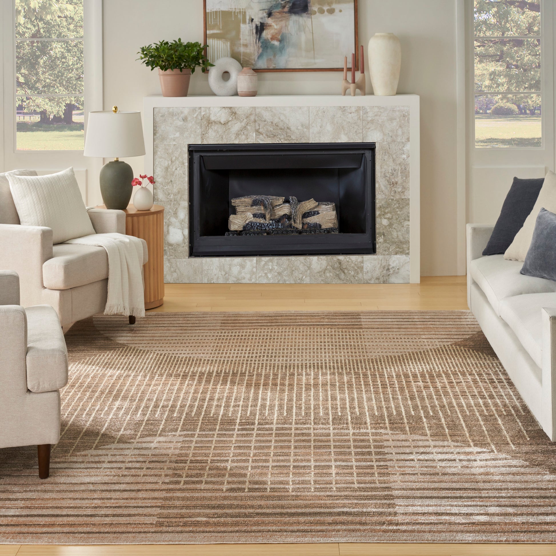 Neutral living room with a tan striped mid-century modern rug (9' x 12'), beige sofas, a marble fireplace with a black insert, a potted plant, and abstract art.