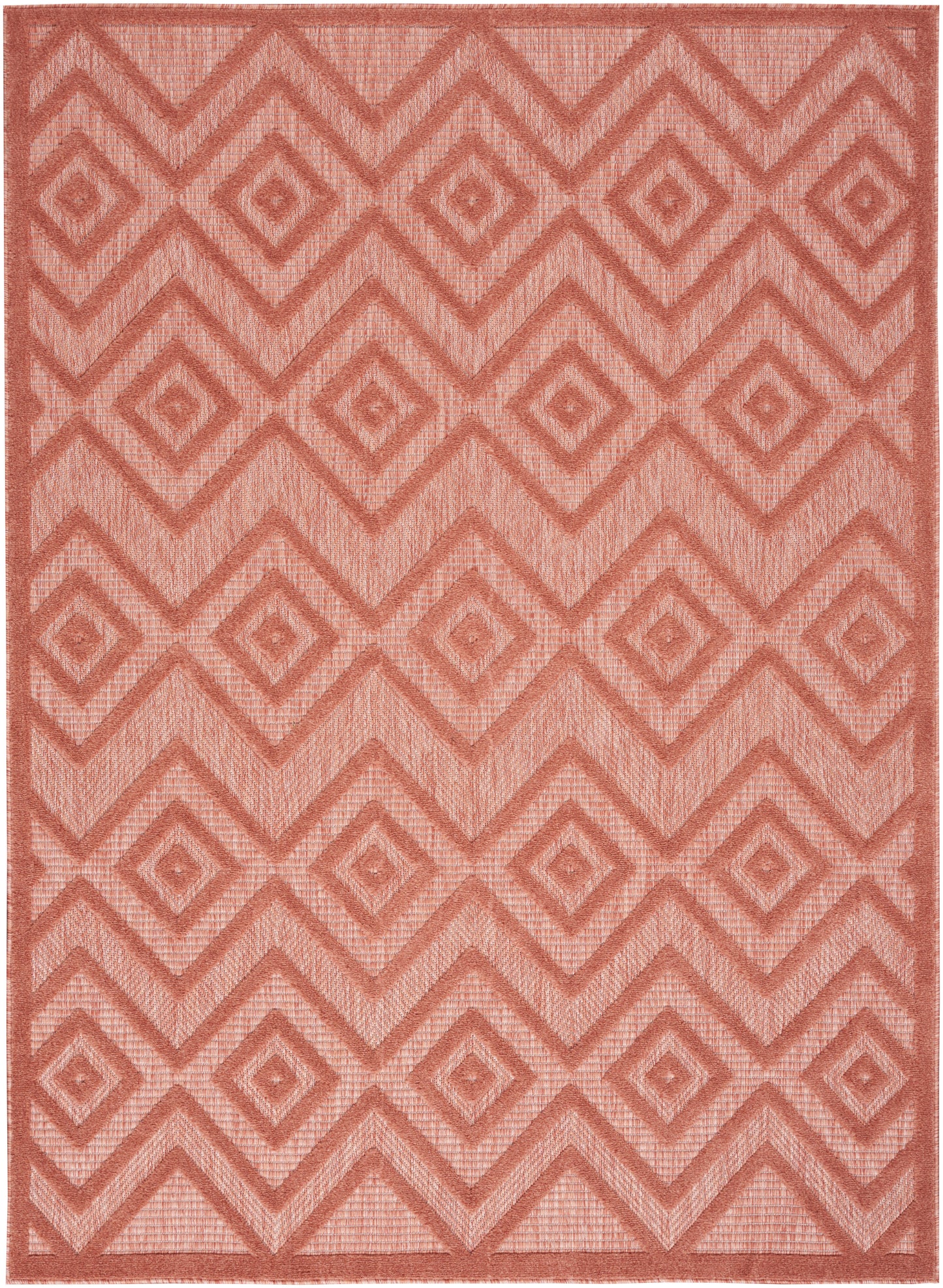 Coral-pink woven rug featuring a repeating diamond and chevron pattern with a textured surface.
