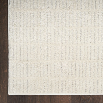 Ivory textured area rug with raised vertical stripe pattern and white border on dark hardwood floor.