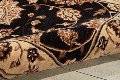 Close-up of oriental floral rug with beige, cream, brown and black colors and a thick pile on a wooden floor.