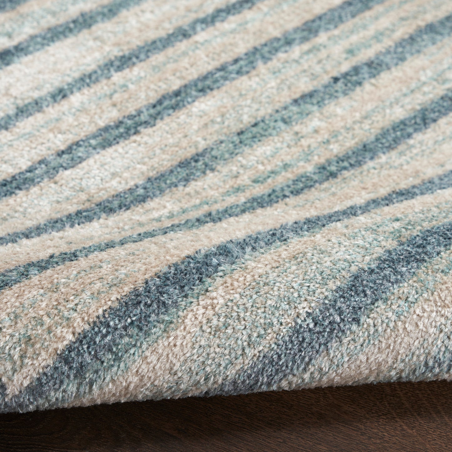 Close-up of a beige rug with blue striped pattern, soft pile and woven texture.