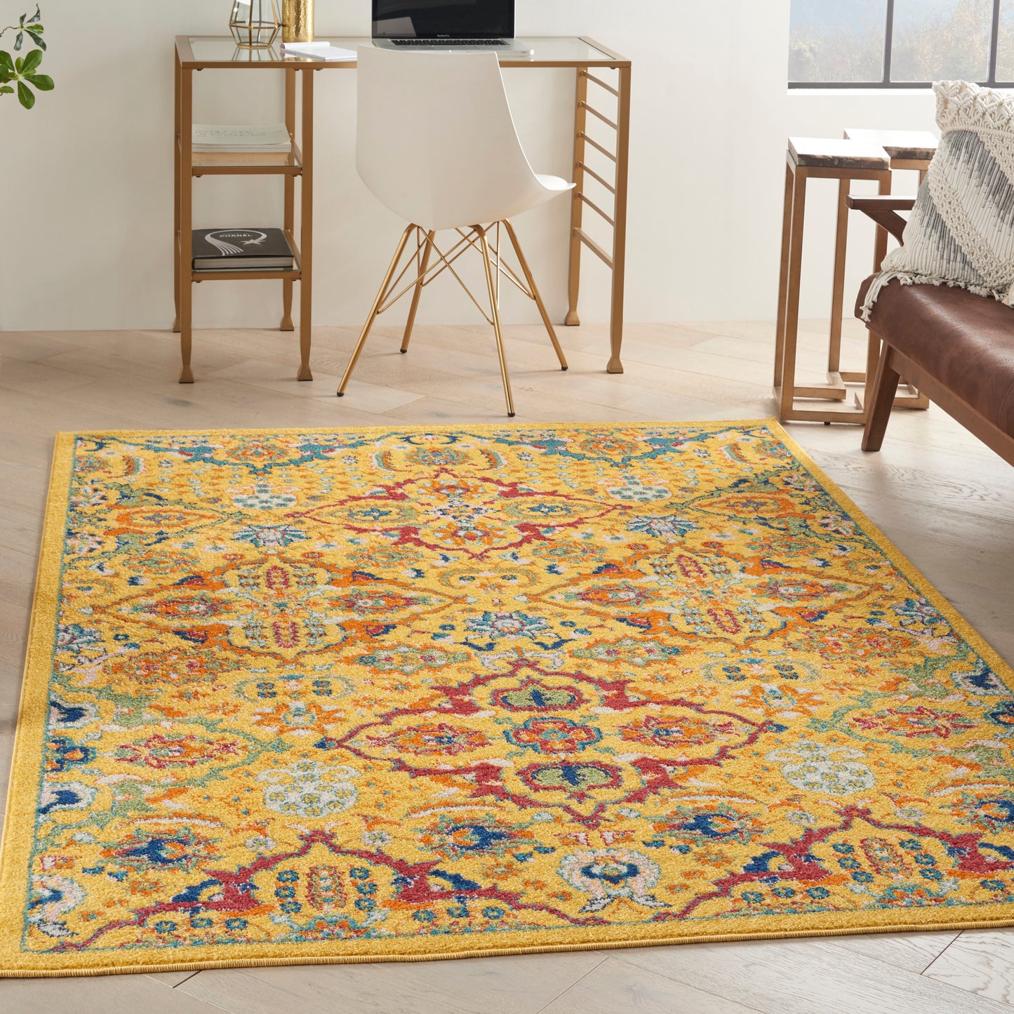 Rectangular vibrant yellow oriental area rug with blue, red and teal floral medallions in a bright home office setup.