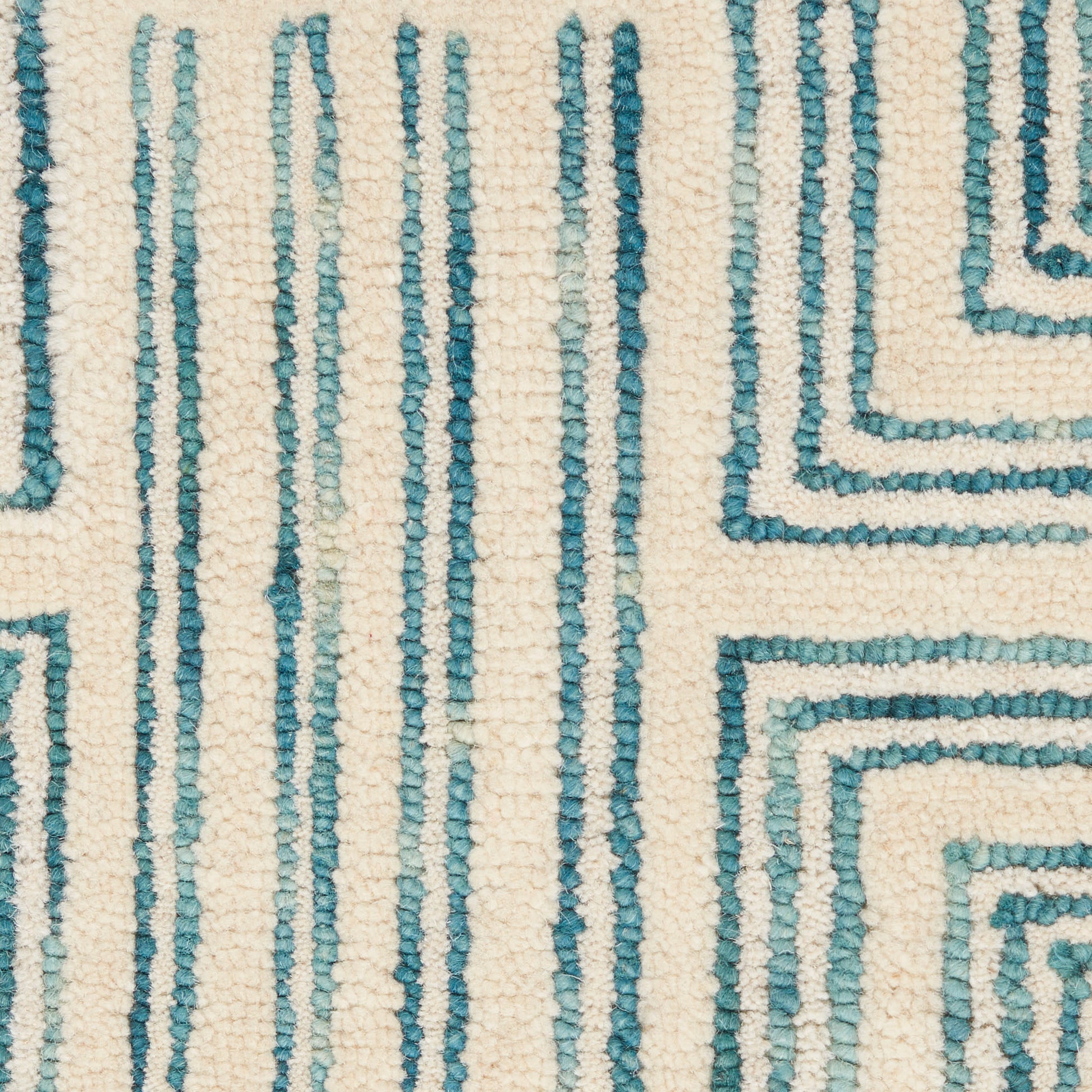 Cream rug with teal geometric maze pattern, vertical lines and square spirals, woven texture.