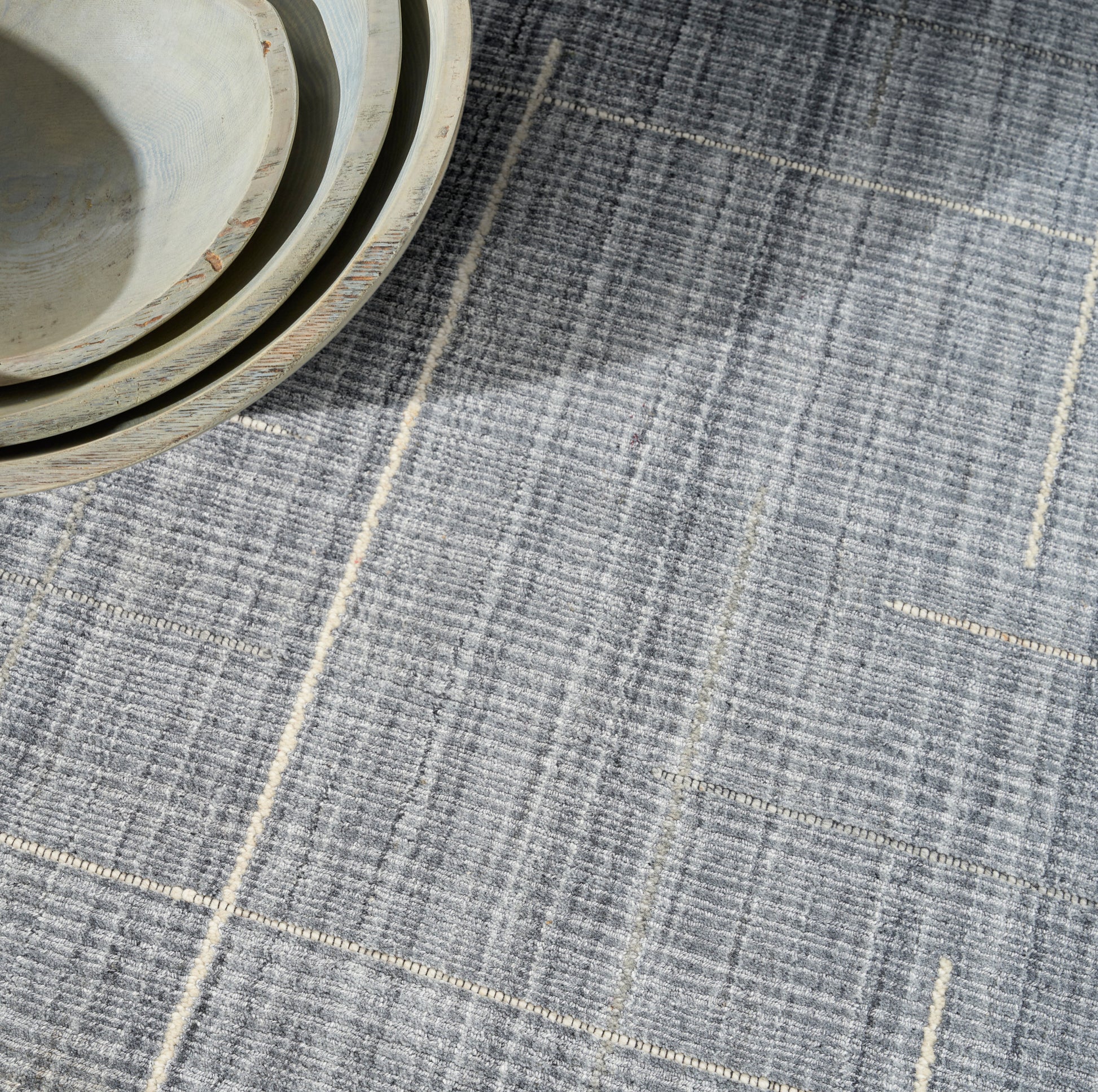 Blue-gray textured rug with pale beige lines.