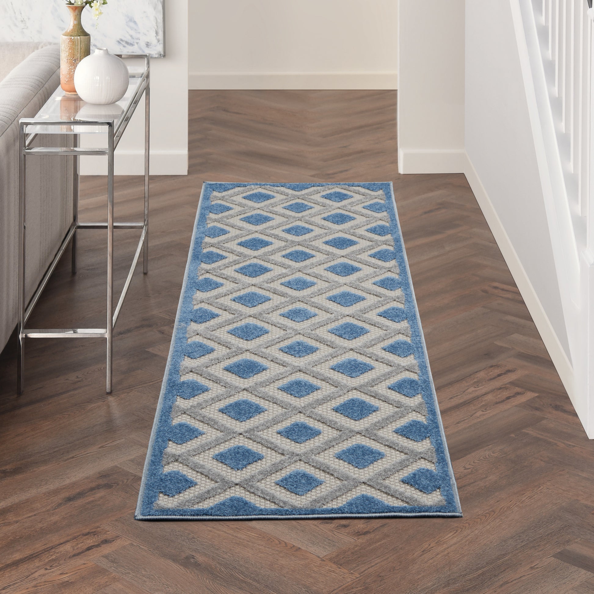 Long blue and ivory geometric diamond runner rug in a hallway with a blue border.