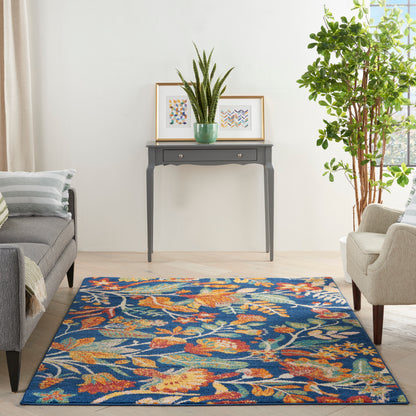 Rectangular blue floral area rug with orange and beige accents on a light wood floor in a modern living room.
