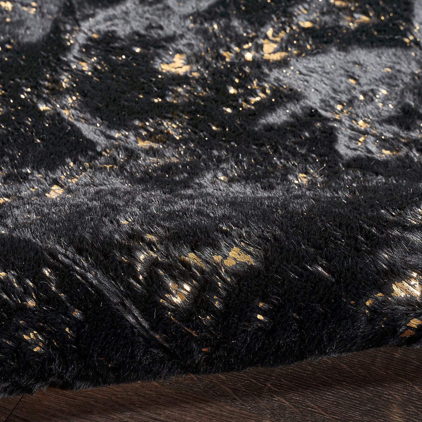Black plush velvet fabric with gold metallic flecks, luxurious soft throw or rug texture.