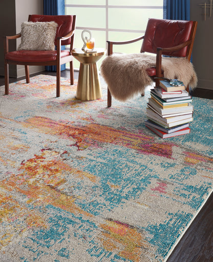 Vibrant abstract area rug in teal, orange, yellow & pink in a living room, with red leather chairs, fur throws and a gold side table; size 7' x 10'.