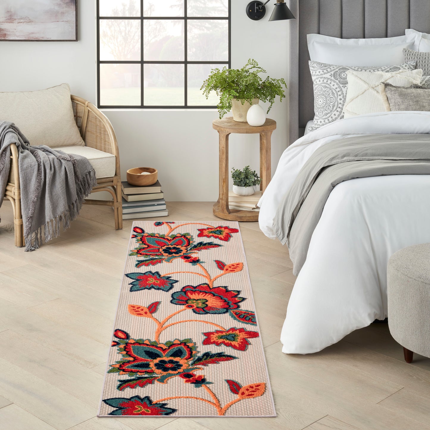 Woven floral outdoor runner rug with bold red, teal and orange flowers on a beige background.