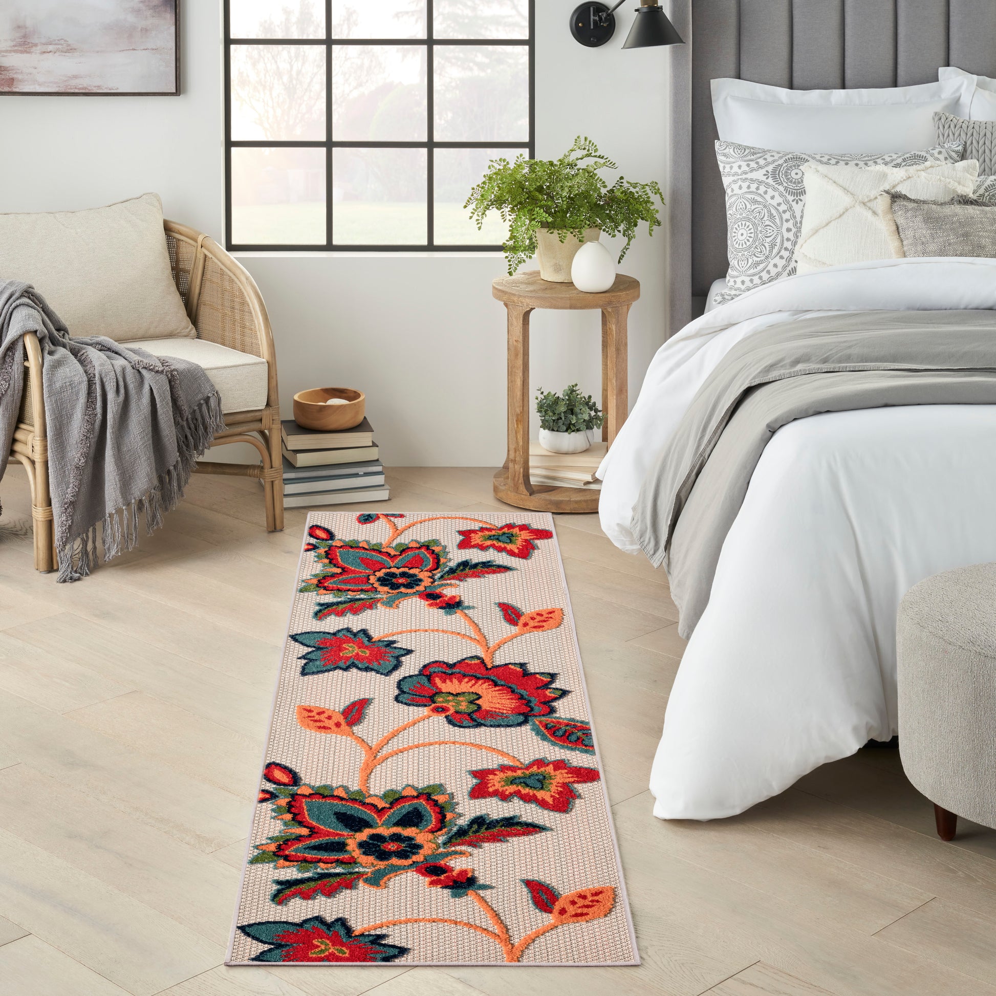 Woven floral outdoor runner rug with bold red, teal and orange flowers on a beige background.