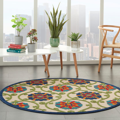 Circular rug with cream backdrop, blue floral motifs, green vines, navy edge; living room with plants & coffee table.