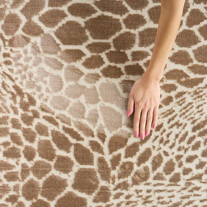 Giraffe-print rug in beige and brown; plush textured surface with irregular spots, hand with pink nails resting on it.
