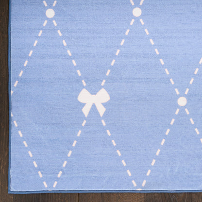 Blue plush rug with white dashed diamond lattice and bow motif, on dark wood floor.