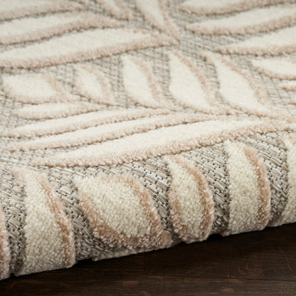 Close-up of plush cream and gray rug with raised leaf pattern and rolled edge on dark wood floor.