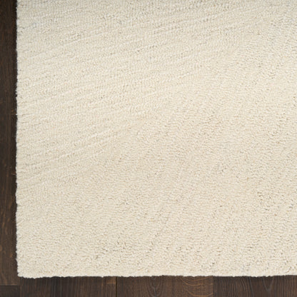 Beige shag area rug with plush pile on dark wood floor; left edge shows a darker border.