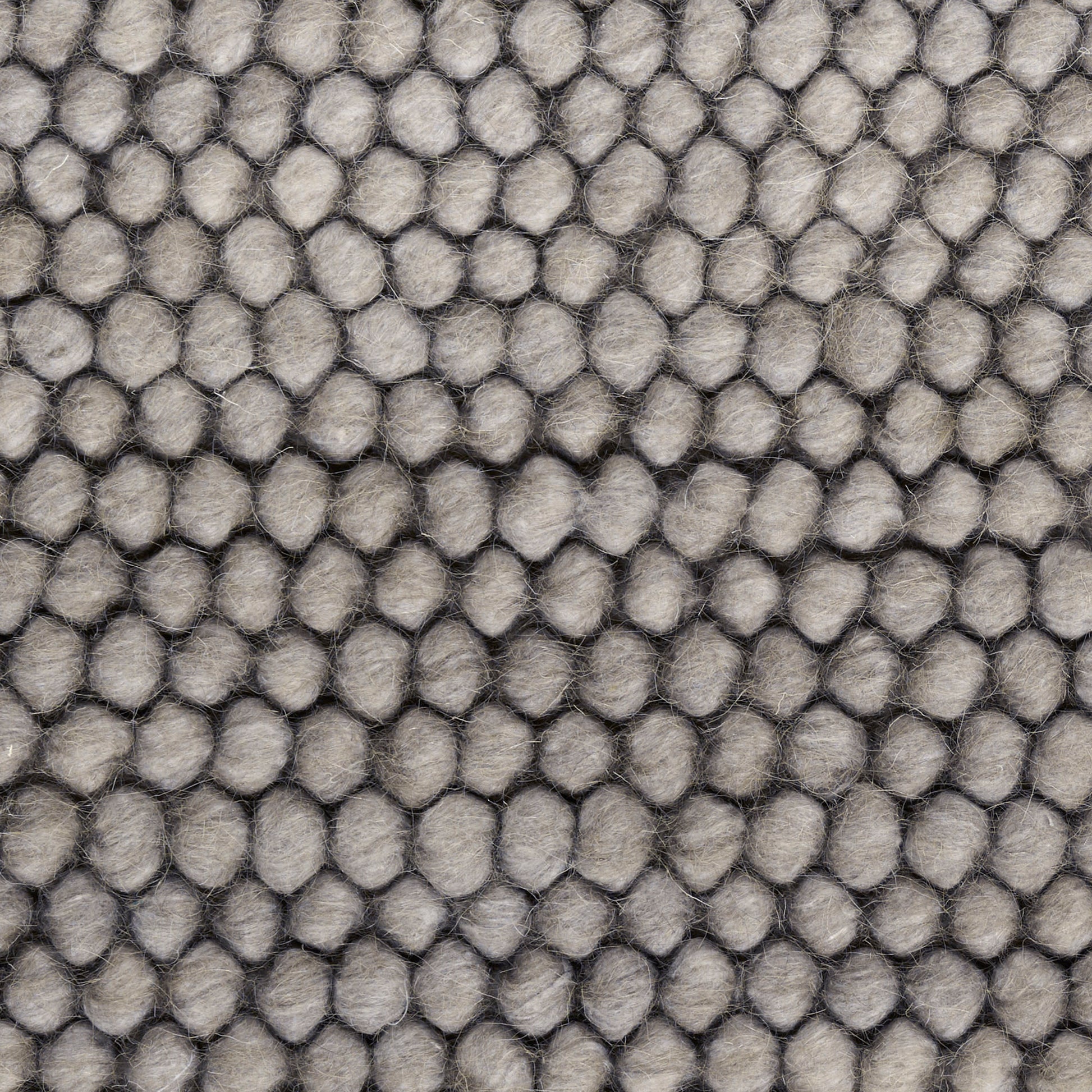 Close-up of gray pebble-textured fabric with rounded tufted bumps in a honeycomb pattern.