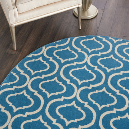 Blue-gray gradient round rug on wood floor with teal patterned border at the edge.