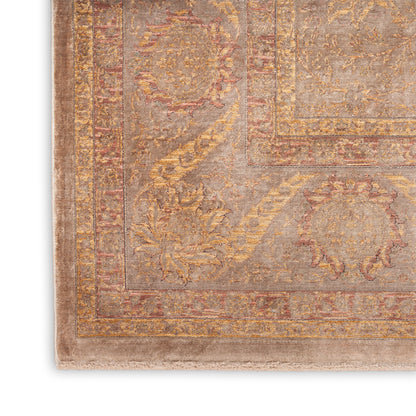 Close-up of a vintage oriental rug with muted taupe, gold and rose tones, ornate floral border and fringe.