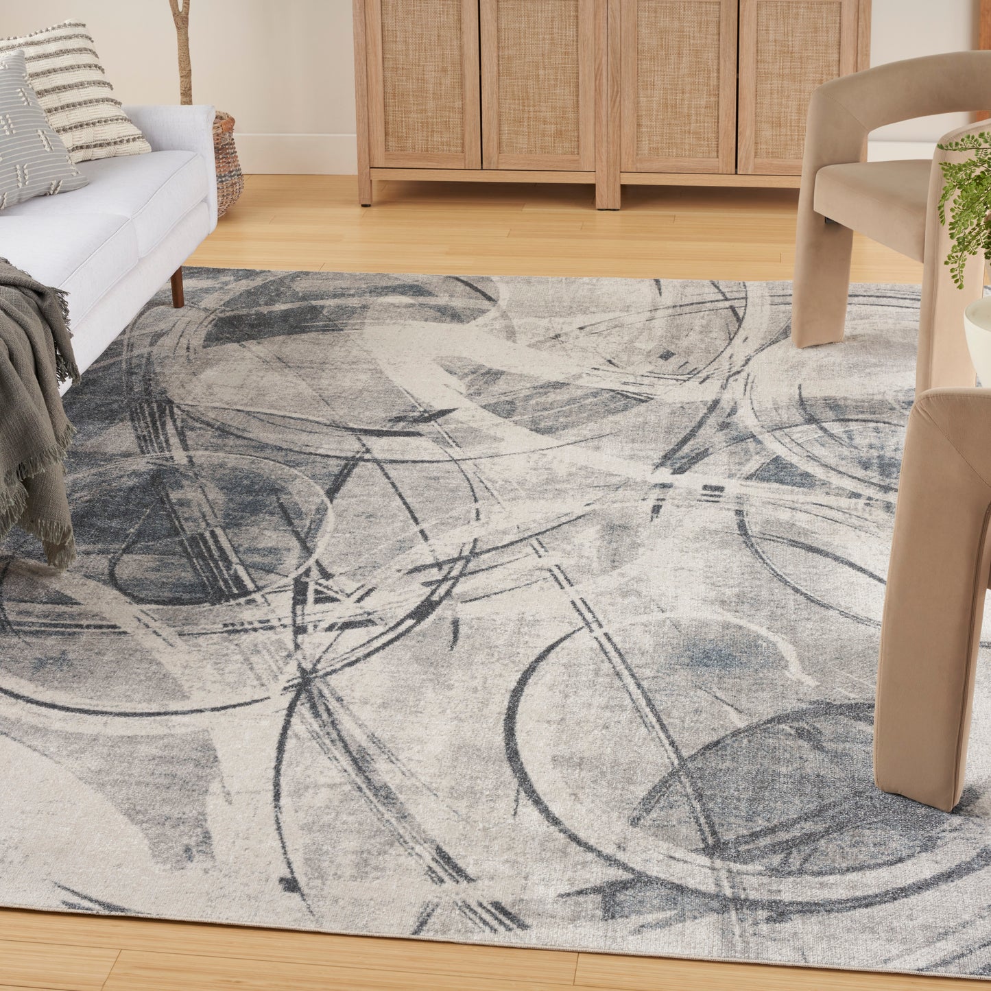 Abstract gray area rug with circular arc patterns on a light beige background in a living room.