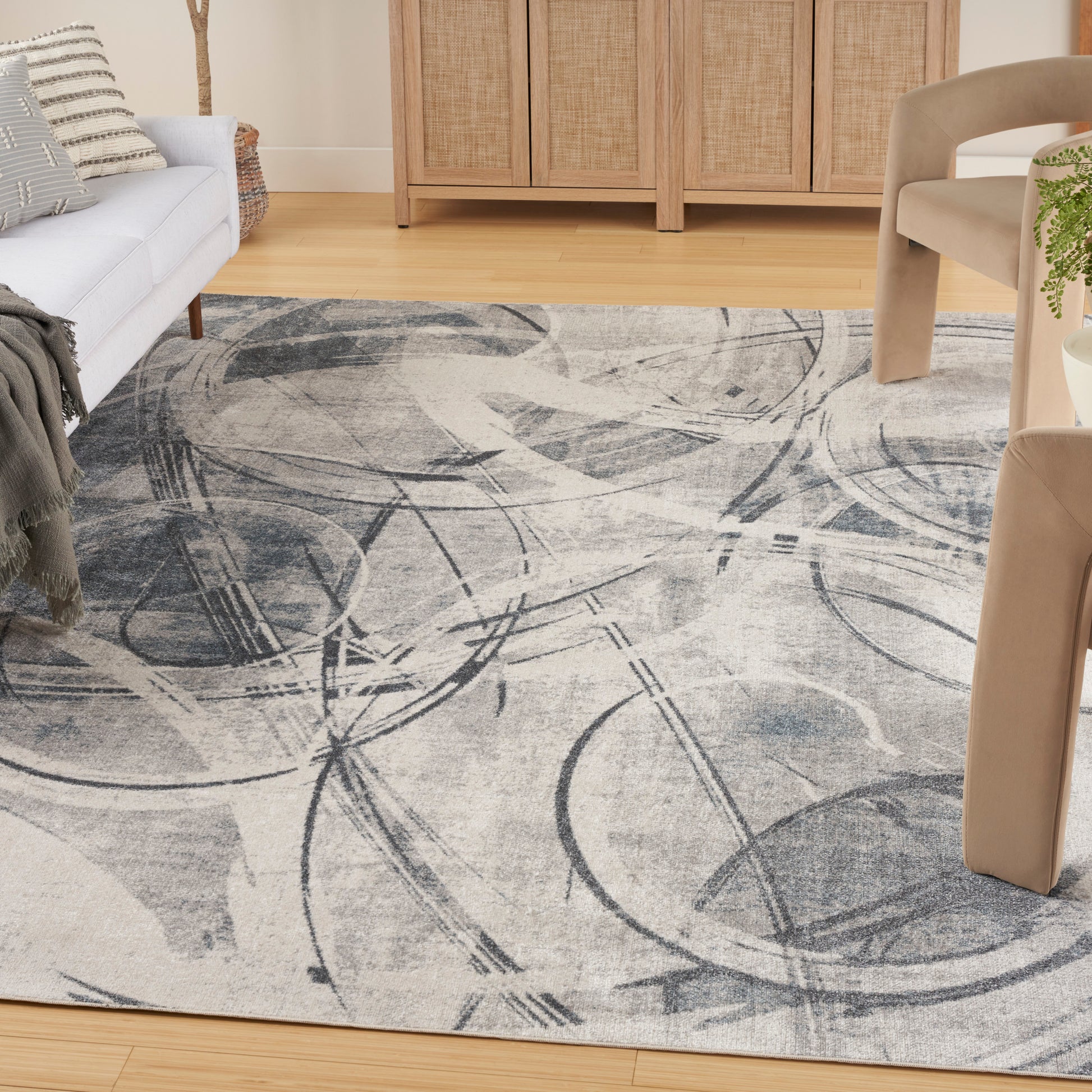 Abstract gray area rug with circular arc patterns on a light beige background in a living room.