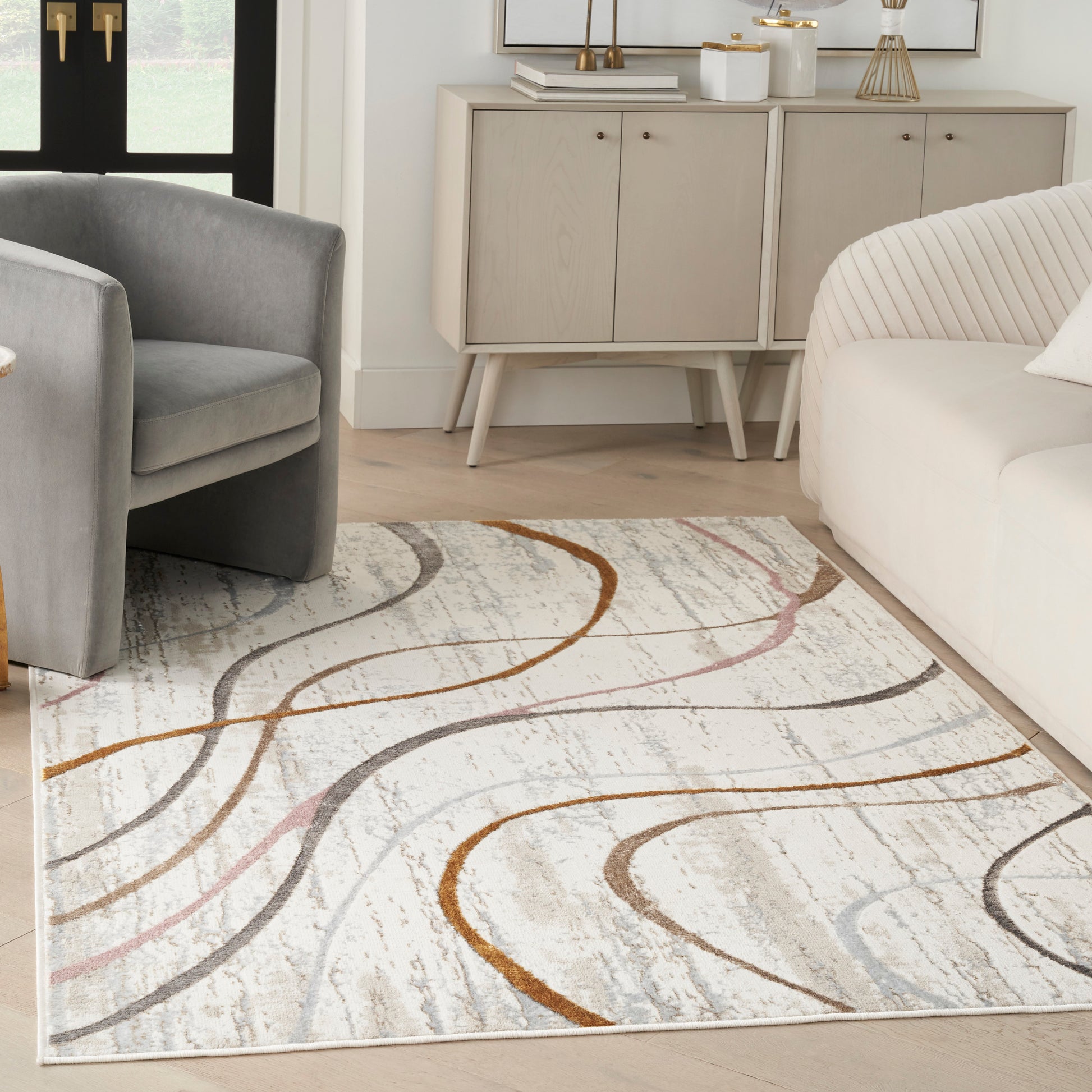 Modern living room with a light area rug displaying orange and gray curved lines, gray armchairs, and a beige cabinet.