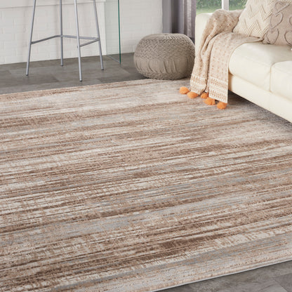 Neutral beige-brown striped area rug in a modern living room with a cream sofa and knit pouf.