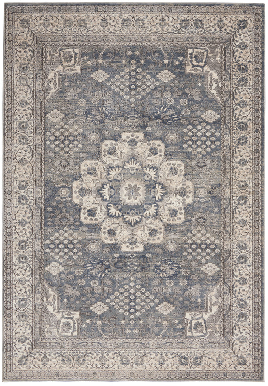 Blue-gray oriental rug with distressed ivory central medallion, ornate floral border and geometric corner motifs.